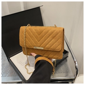 Detail of yellow quilted suede bag with gold chain strap and metallic buckle