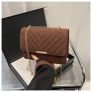 Detail of brown suede crossbody bag with V-shaped quilting and gold metal chain strap