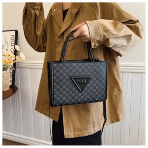 Close-up of geometric pattern tote bag featuring a leather triangle patch with bag lettering