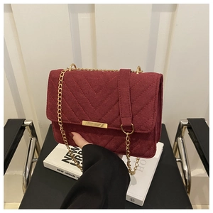 Close-up of burgundy quilted velvet handbag with gold chain strap and square lock