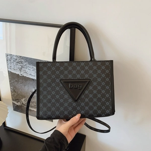 Detail of large tote bag showing dark blue cross pattern and embossed triangle bag logo