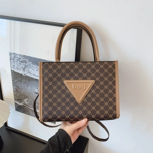 Detail of vintage brown tote bag with cross pattern and embossed leather triangle logo