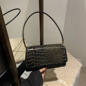 Chic black baguette shoulder bag with gold embossed flap and sleek metal accents
