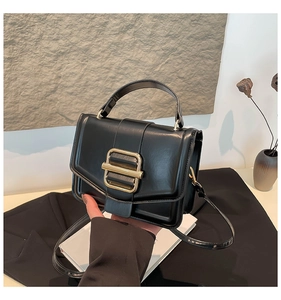 Detail of black matte leather handbag with gold square buckle and single handle strap