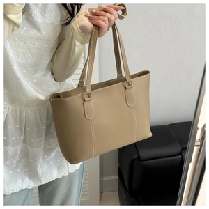 Detail of khaki tote bag featuring contrast white stitching and gold metal hardware