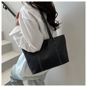 Detail of black leather tote bag with white contrast stitching on a model side view