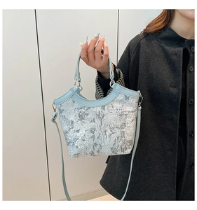 Detail of light blue silk embroidery handbag featuring silver floral patterns and leather trim