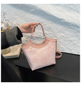 Detail of pink jacquard handbag with floral embroidery and leather trim held by hand