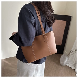 Detail of caramel brown leather tote bag with white stitching shown on shoulder