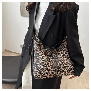 Detail of leopard print tote bag with black drawstring bow and sleek leather shoulder strap