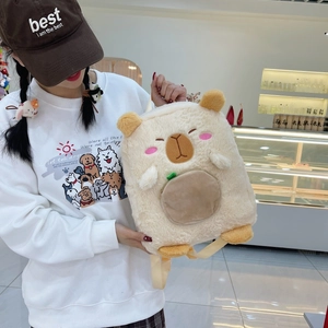 Detail of cute beige Capybara plush backpack with soft fur and leaf decoration