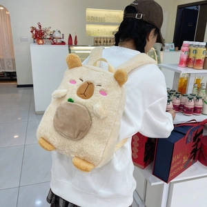 Detail view of a cute plush capybara backpack with embroidered eyes and front pocket