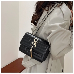 Close-up of black quilted leather shoulder bag featuring a gold buckle and chain tassel