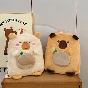 Detail of plush capybara backpacks in white and brown with leaf zipper on wooden surface