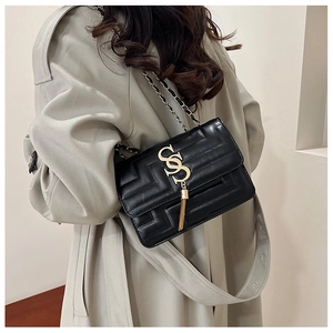 Detail of black quilted leather shoulder bag with gold tassel and chain strap