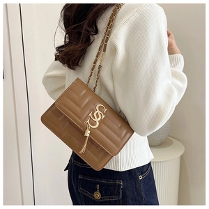 Detail of caramel leather crossbody bag with geometric quilting and golden tassel metal logo