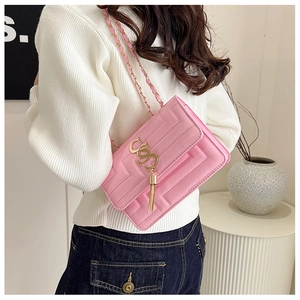 Close-up of pink quilted crossbody bag with golden tassel and chain strap detail