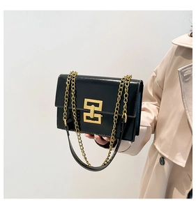 Close-up of sleek black square bag with premium gold chain strap and metallic buckle
