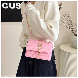 Detailed shot of pink quilted crossbody bag featuring golden S-pendant and fringe