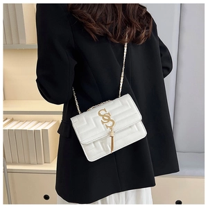 Detail view of a white quilted crossbody bag with gold tassel logo and chain strap