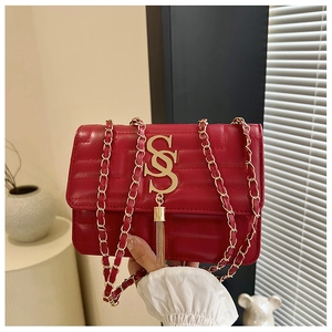 Detail of red quilted leather crossbody bag with gold metal logo and fringe tassel