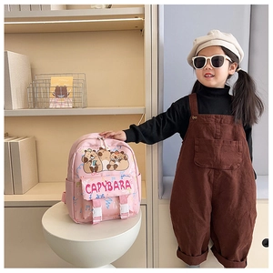 Zaino rosa per bambini con motivo capibara indossato da un modello in un interno