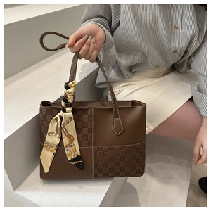 Dettaglio della borsa tote marrone con patchwork a scacchi ed elegante foulard di seta