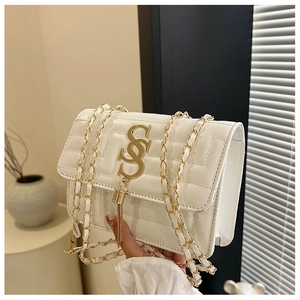 Close-up of white quilted leather crossbody bag with gold metal logo and tassel detail