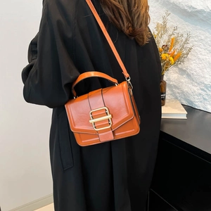 Retro caramel square crossbody handbag with gold lock shown in a lifestyle urban setting