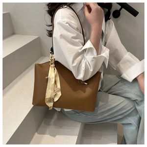 Brown leather tote bag detail with silk scarf on model in casual urban setting