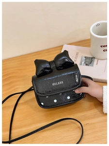 Detalle del bolso bandolera negro con un lazo grande y un estampado de lunares blancos