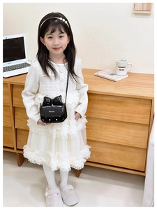 Primer plano de un mini bolso de charol negro con un lazo grande y estampado de lunares