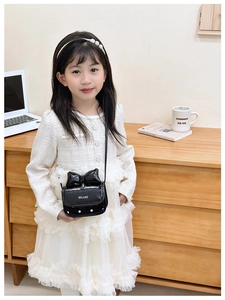 Minibolso bandolera para niña con lazo grande y lunares blancos sobre un fondo negro brillante