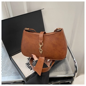 Detail of vintage brown baguette bag featuring textured leather and metal clasp hook