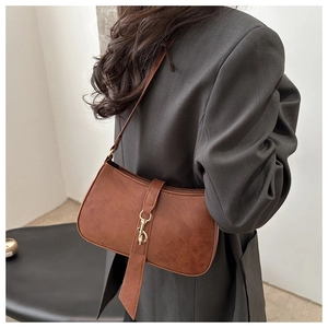 Detail of dark brown leather baguette bag featuring a vintage golden lobster clasp hook