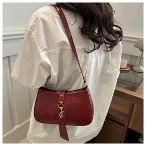 Detailed view of a dark red vintage leather underarm bag with metal hook on white shirt