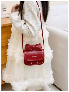 Detalle de un bolso bandolera rojo para niñas con lazo y acabado en cuero PU pulido