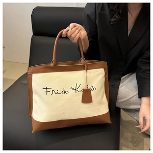 Detailed shot of canvas tote bag with brown leather trim and Frida Kahlo lettering