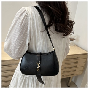 Classic black leather shoulder bag with gold metal hook detail shown in lifestyle setting