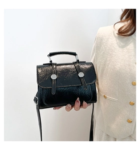 Détail du sac messager noir à texture froissée avec boucles argentées et anse
