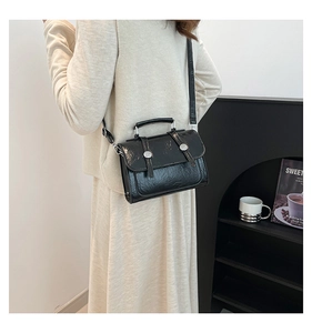 Détail du sac bandoulière vintage en cuir huilé noir avec boucles argentées décoratives