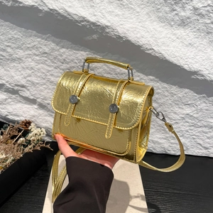 Détail d'un sac bandoulière doré métallisé avec texture froissée et boucles argentées