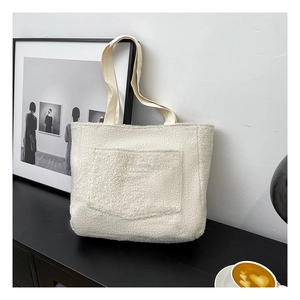 Dettaglio della borsa tote in pile peluche con tasca frontale ed etichetta FASHION crema
