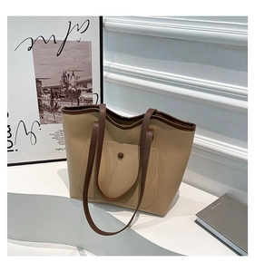 Detail of a large khaki and brown leather tote bag with a front snap pocket and fine stitching