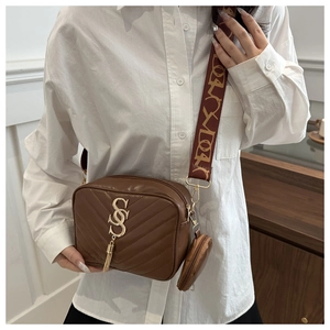 Detail of dark brown quilted camera bag with golden S-pendant and jacquard strap