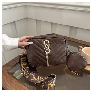 Detail of dark brown V-quilted crossbody bag with gold logo, tassel and patterned strap