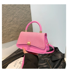 Close-up of pink crossbody bag with woven texture lid and golden metal lock detail