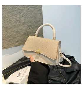 Close-up of beige leather and brown woven flap handbag with golden buckle detail