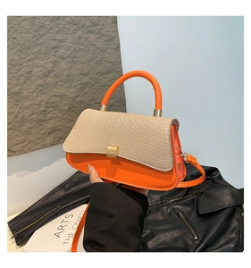 Detailed view of the bright orange handbag with beige woven flap and gold metal hardware