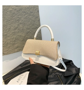 Detail of elegant two-tone handbag with khaki straw texture and gold metal buckle